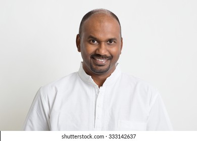 Portrait Of Mature Casual Business Indian Man Smiling, Standing On Plain Background With Shadow.