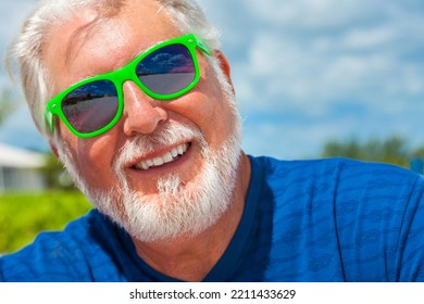 Portrait Of Mature Caucasian Male In Bright Clothes And Sunglasses Carefree Outdoors By The Ocean On Luxury Travel Beach Resort 