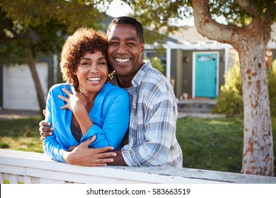 Portrait Of Mature Couple Looking Over Back Yard Fence