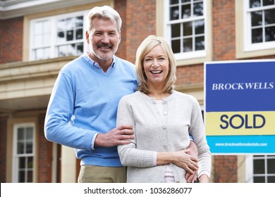 Portrait Of Mature Couple Outside New Home Standing By Sold Sign