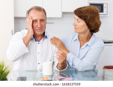 Portrait of mature family couple sitting at kitchen table and taking medicine - Shutterstock ID 1618137559
