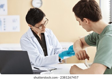 Portrait of mature female doctor inspecting patient with skin rash during consultation in dermatology clinic - Powered by Shutterstock