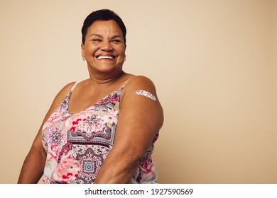 Portrait of a mature female smiling after getting a vaccine. Woman looking away and smiling after receiving vaccination. - Powered by Shutterstock