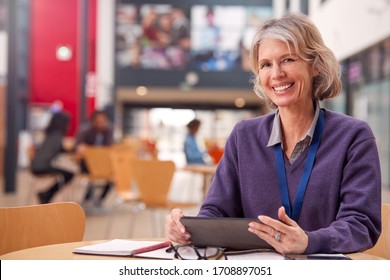 Portrait Of Mature Female Teacher Or Student With Digital Tablet Working At Table In College Hall