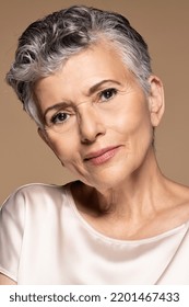 Portrait Of A Mature Latina Woman Smiling On A Neutral Background.