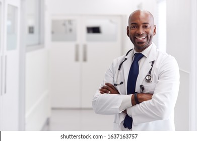 Portrait Of Mature Male Doctor Wearing White Coat Standing In Hospital Corridor - Powered by Shutterstock