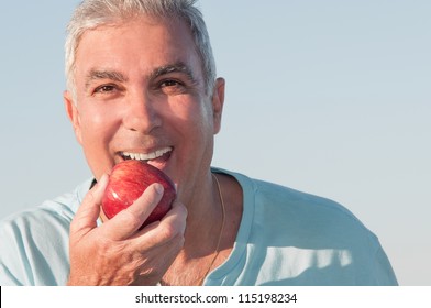 Porträt eines reifen Mannes, der kurz davor steht, einen roten Apfel zu essen