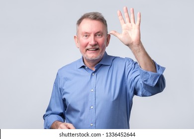 Portrait Of A Mature Man In Blue Shirt Wave Hand Welcome.