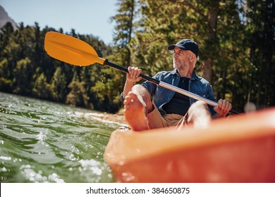 Portrait of a mature man with kayak in a lake. Caucasian man paddling a kayak on summer day. - Powered by Shutterstock