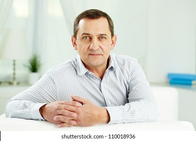 Portrait Of Mature Man Looking At Camera While Sitting On Sofa