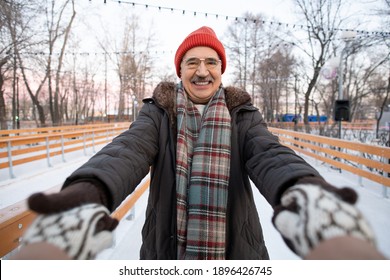 Portrait Of Mature Man Smiling At Camera And Holding Hands Of His Wife During Their Ride On Skating Rink