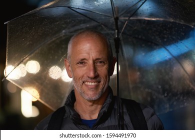 Portrait mature man smiling under umbrella standing in rain enjoying rainy urban evening insurance concept testimonial