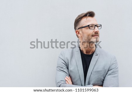 Portrait of mature man wearing grey jacket standing against white wall with copy space