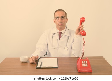 Portrait Of Mature Persian Man Doctor Behind Desk