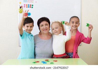 Portrait Of Mature Preschool Teacher And Children In A Classroom During Class