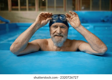 Portrait of mature senior man wearing swimming hat and goggles at pool - Powered by Shutterstock