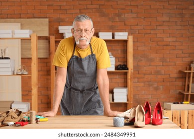 Portrait of mature shoemaker at table in workshop - Powered by Shutterstock