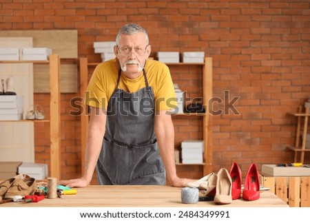 Portrait of mature shoemaker at table in workshop