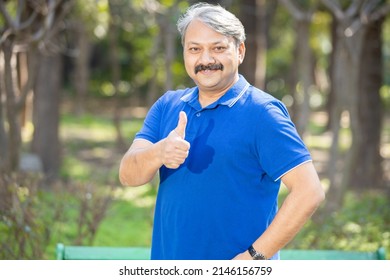 Portrait mature smiling indian senior man standing at park doing thumbs up gesture, Happy Elderly white-haired people smiling carefree,old mustache male with positive emotion. all good expression.