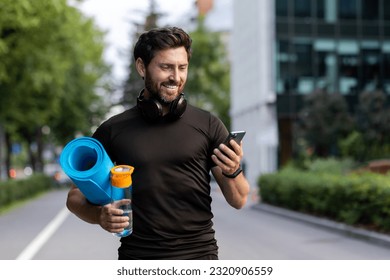 Portrait of mature successful adult athlete, bearded man going to workout, coach holding fitness mat and phone, browsing online app for joint physical training. - Powered by Shutterstock