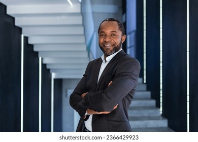 Portrait of mature and successful businessman inside office, boss smiling and looking at camera with crossed arms, african american man in business suit happy with successful achievement results.