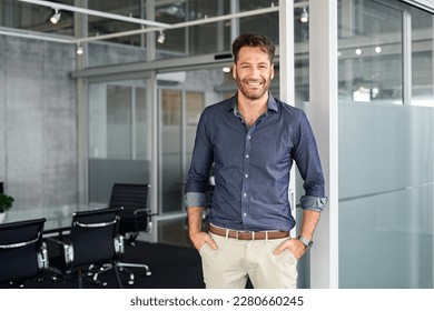 Portrait of mature successful man with hands in pocket standing outside office conference room. Businessman standing in office while looking at camera. Satisfied man in formalwear with copy space. - Powered by Shutterstock