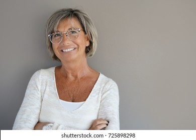 Portrait of mature woman with eyeglasses on grey background