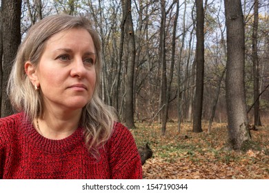 Portrait Of Mature Woman In Knitwear In Autumn Forest. Girl Does Not Look At Camera. No Smile. Thought, Meditation Or Doubt Expression. Relax Or Other Mental Psychology Concept