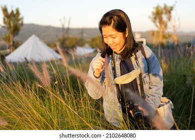 Portrait Of Mature Woman Looking At Flowers In Meadow Field