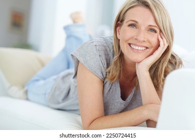 Portrait of mature woman lying on sofa in living room, happiness and relaxing in comfort at home. Smile, lazy weekend time and happy woman in peace chilling on comfortable couch in apartment on break - Powered by Shutterstock