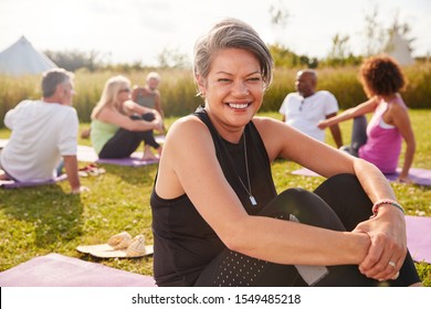 Portrait Of Mature Woman On Outdoor Yoga Retreat With Friends And Campsite In Background