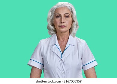 Portrait Of Mature Woman Scientist Or Doctor Looking At Camera. Senior Woman In White Coat Posing On Green Background.