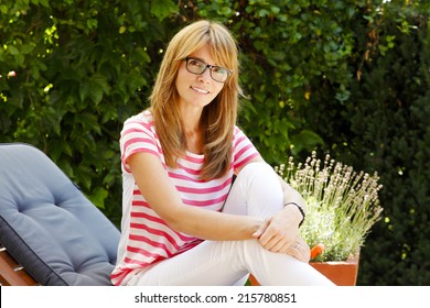 Portrait Of Mature Woman Sitting At Garden.