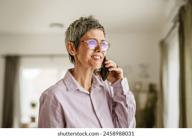 Portrait of mature woman stand and talk on mobile phone with dear peson at home - Powered by Shutterstock