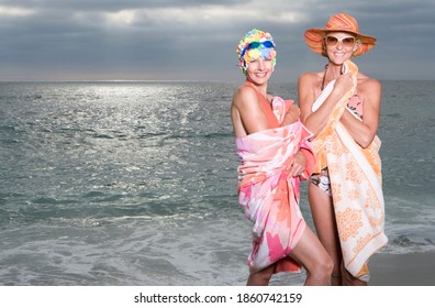 Portrait Of A Mature Woman In Swimming Cap By A Friend In Sunhat On The Beach.