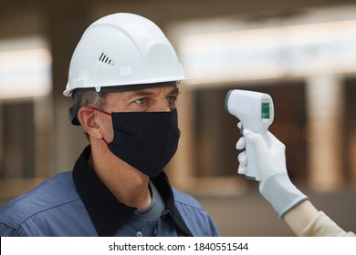 Portrait Of Mature Worker Wearing Mask And Waiting To Measure Temperature With Contactless Thermometer At Construction Site, Corona Virus Safety