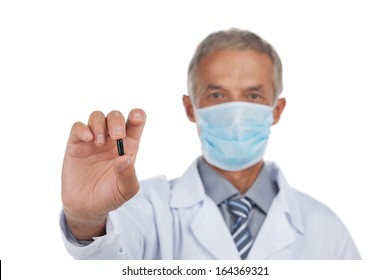 Portrait Of Mean Age Doctor. Holding Black Pill In Hand. Isolated On White  