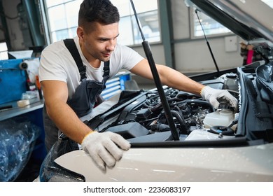 Portrait of mechanic checking parts of automobile