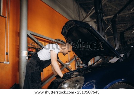 Portrait of mechanic checking parts of automobile.