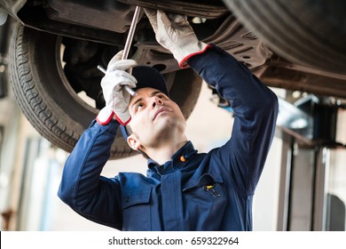 Portrait of a mechanic repairing a lifted car - Shutterstock ID 659322964