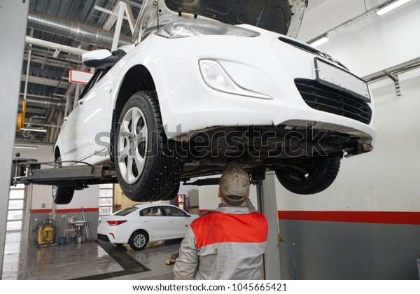 Portrait of a\
mechanic repairing a lifted\
car