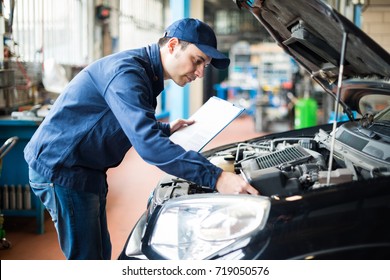 Portrait of a mechanic at work in his garage - Shutterstock ID 719050576