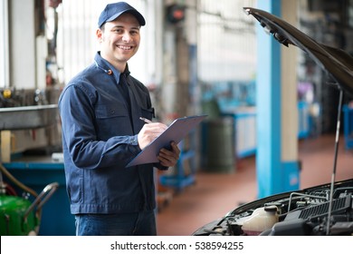 Portrait of a mechanic writing on a clipboard in his garage - Shutterstock ID 538594255