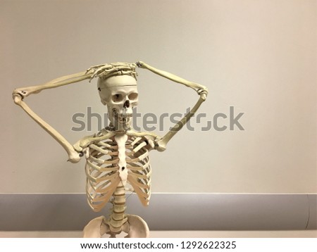 portrait of a medical skeletal model with hand over the skull on vintage style background in an operating room
