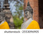 Portrait of meditating Buddha stone statue with golden robe at Wat Yai Chai Mongkol on blurred background in Ayutthaya, Thailand