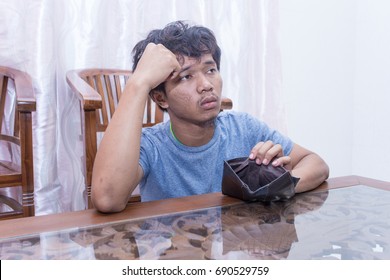 Portrait messed young Asian man wearing blue shirt stressed because of empty wallet, no money isolated. Businessman, salary, economic problem concept. Asia people