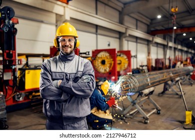 Portrait of metallurgy worker standing in factory and smiling at the camera. - Shutterstock ID 2127946712