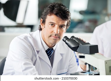 Portrait Of Mid Adult Male Scientist Using Microscope In Laboratory