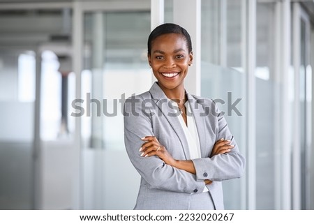 Portrait of mid adult successful black mature woman looking at camera with arms crossed. Smiling african american business woman standing in new office with copy space. Portrait of mature woman.