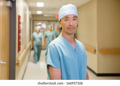 Portrait Of Mid Adult Surgeon With Team Walking In Hospital Corridor